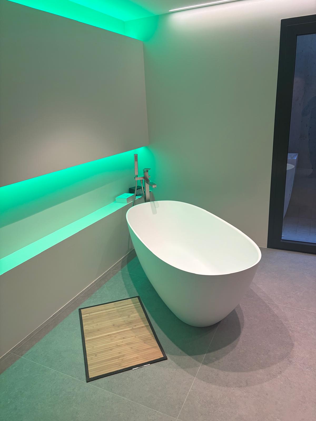 Bagno con vasca freestanding e luce verde